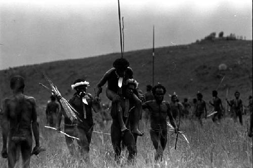 Wounded warrior being carried from the battle front on the shoulders of another warrior