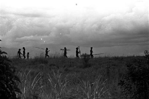 Silhouetted figures with spears coming back along the Tokolik