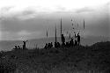 Silhouetted figures with spears sitting along the Tokolik