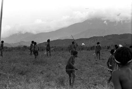 Boy in shorts running back from the front, warriors in action beyond him