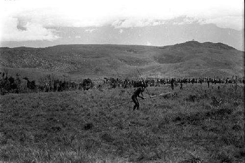 Distant view of Willihiman-Wallalua warriors out at the front lines with their spears, Wittaia beyond them; man in foreground holding multiple spears