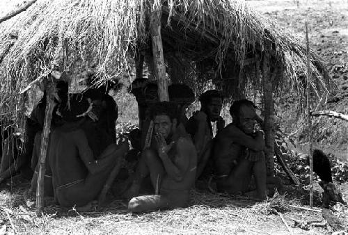 Yegé Asuk and other men sitting under an olea