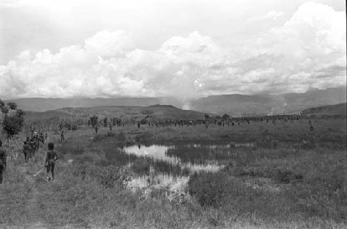 Long line of warriors going past the pond on the wat to a war on the Tokolik