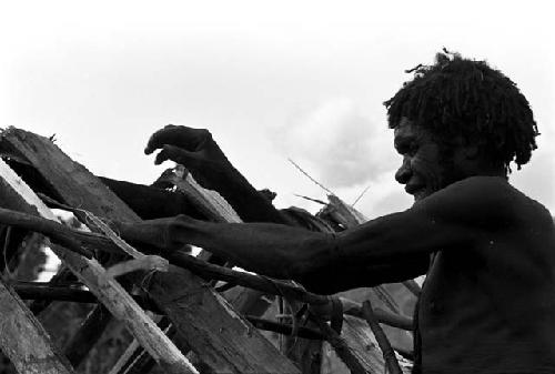 A man assembling the rafters of a lise in the new village of Kumina