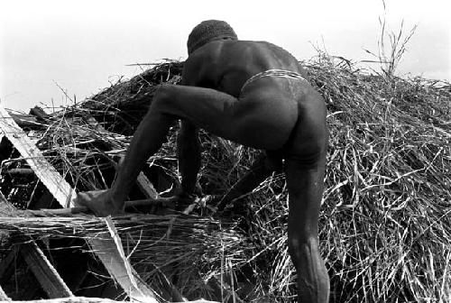 A man thatching the roof of a building under construction in the new village of Kumina