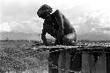 Man working on the sleeping platform of a honai under construction