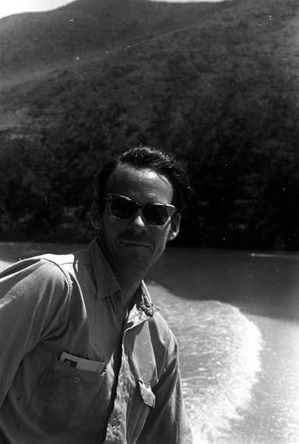 Robert Gardner, in browline sunglasses, taking a boat down the Aikhé River