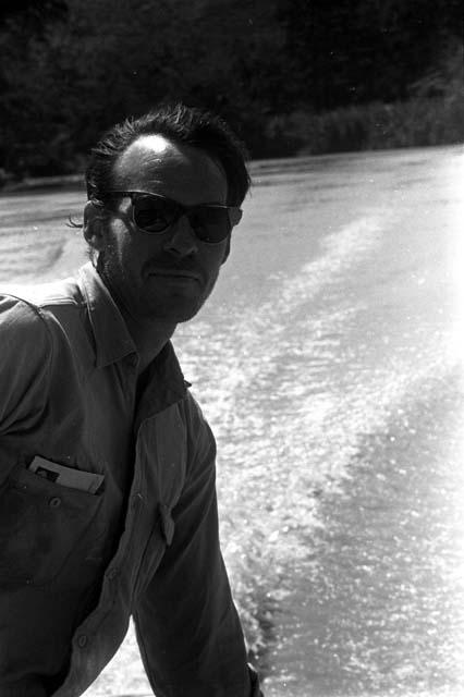 Robert Gardner, in browline sunglasses, taking a boat down the Aikhé River