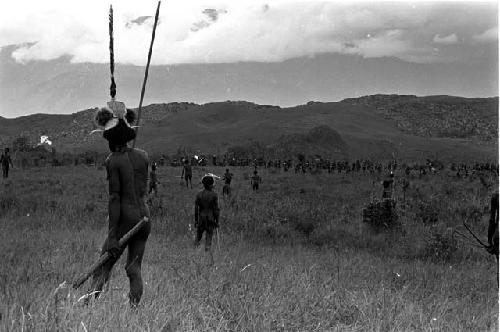 Warrior wearing an inamossi (headdress), action and hills beyond