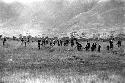 Warriors walking along the Tokolik with weapons in hand; hills beyond