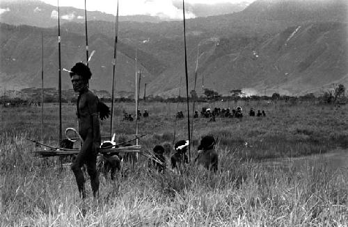 Group of warriors with spears in the foreground, another in the middle ground on the Tokolik; northeastern mountain wall beyond