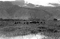 Seated warriors waiting with their spears by a pond, another group in the middle ground; hills beyond