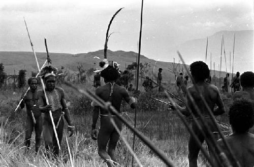 Men with weapons coming back from or going to the battle front, past the pond