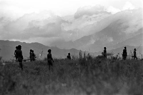 Men with weapons on the Tokolik; hills beyond