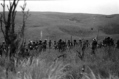 A large group of warriors moving into battle; hills beyond