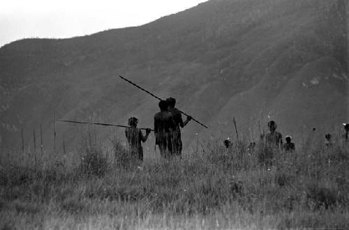 Men watching the distant battle; western mountain wall beyond