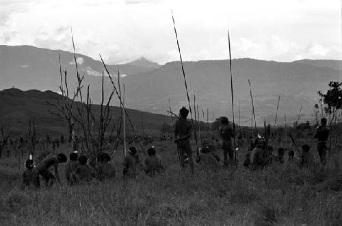 Men waiting with their weapons on the Tokolik; mountains beyond