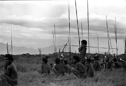 Men and boys waiting for battle to start, spears all around