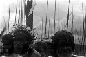 A group of men look towards the camera, very many spears behind them