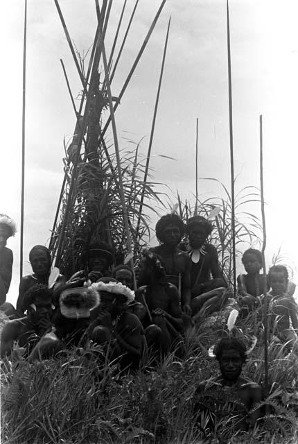 A group of men waiting on the Warabara, with spears stacked behind them