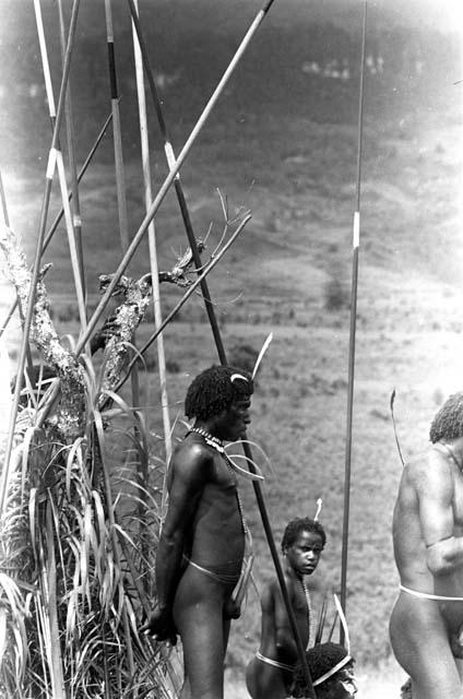 Men standing in front of a pile of spears