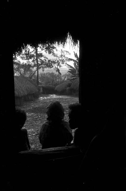 Young boys in the entry of a honai at Wuperainma, looking out towards the sili