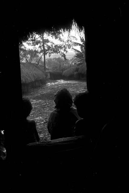 Young boys in the entry of a honai at Wuperainma, looking out towards the sili