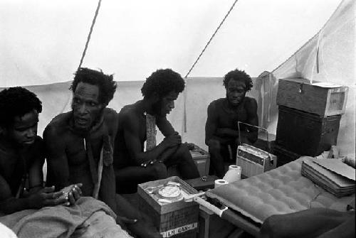 Aloro, Husuk, Loliluk, and Walimo sitting in Robert Gardner's expedition tent