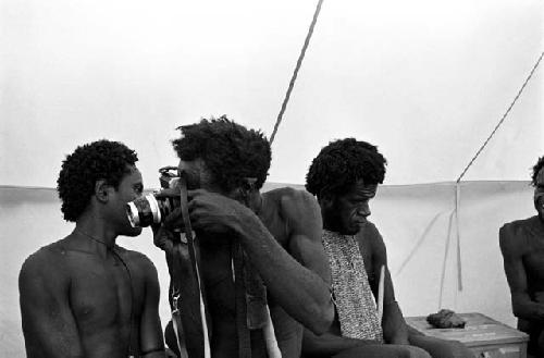 Husuk looking through a Nikon camera in Robert Gardner's tent