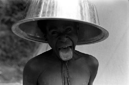 A boy clowning with a wash pan on his head