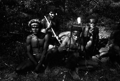 Yegé Asuk using a loom by the fire outside Robert Gardner's tent; others around