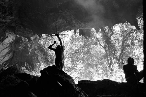 Man shooting an arrow upwards at a bat