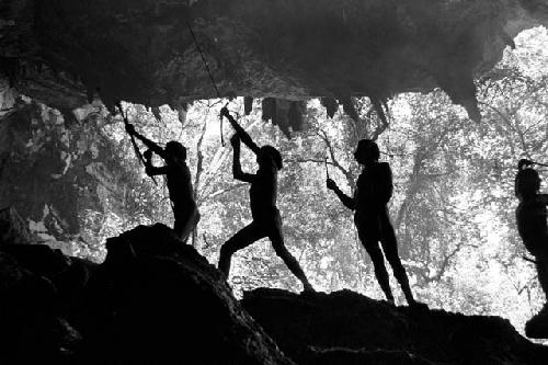 Men shooting arrows upwards at bats