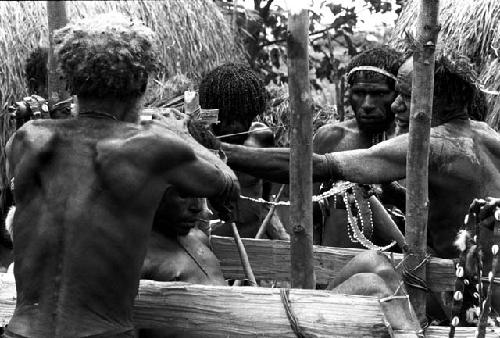 Men bearing cowrie stings to place around the corpse