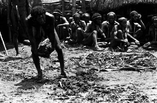 A man spreading out ferns on the ground at Ekiarotmilek's funeral