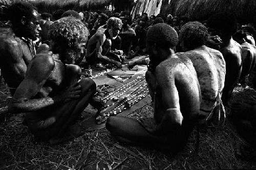 Men looking at cowrie shell strands at Ekiarotmilek's funeral