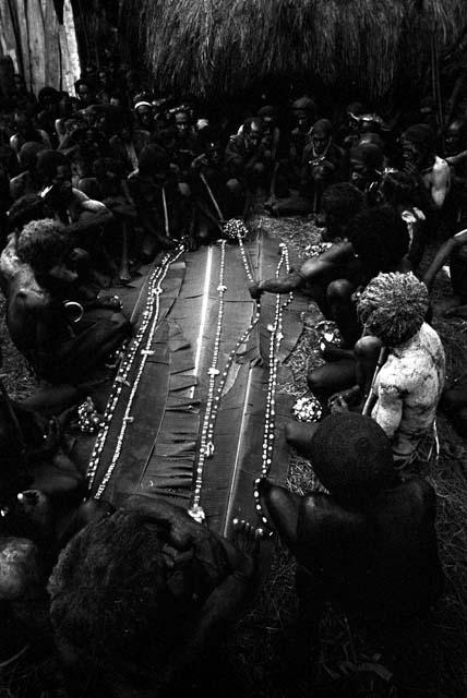 Men looking at cowrie shell strands at Ekiarotmilek's funeral