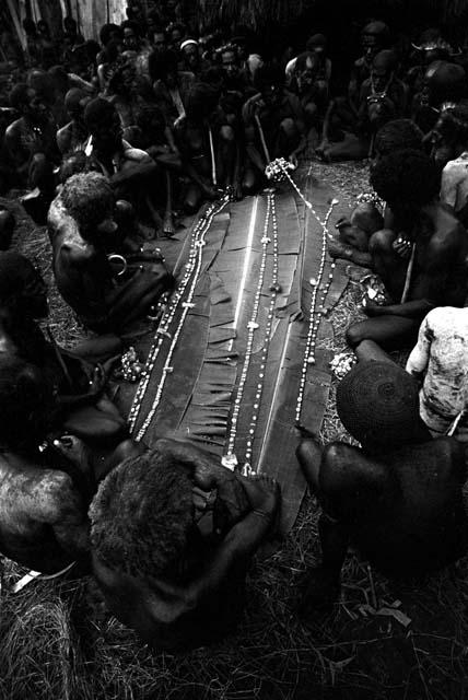 Men looking at cowrie shell strands at Ekiarotmilek's funeral