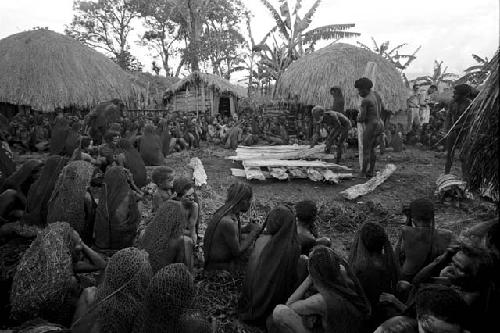 Men begin to build the funeral pyre; mourners all around