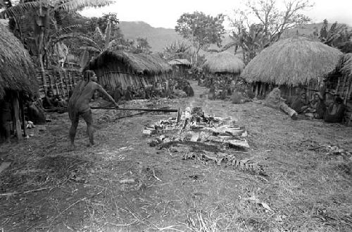 A woman stokes the dying embers of Ekiarotmilek's funeral pyre