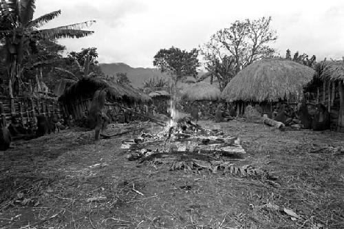 A woman stokes the dying embers of Ekiarotmilek's funeral pyre