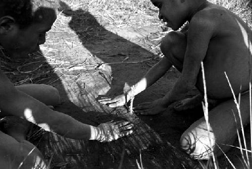 Small children playing a kaio game with munika seeds