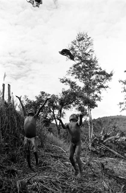 Nameliké (left) and a boy throw sus (carrying nets) into the air