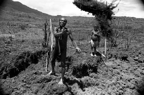 A man works in his garden as his daughter watches