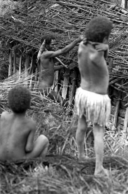 Children watch as a man tears apart an old hunu in Abukulmo