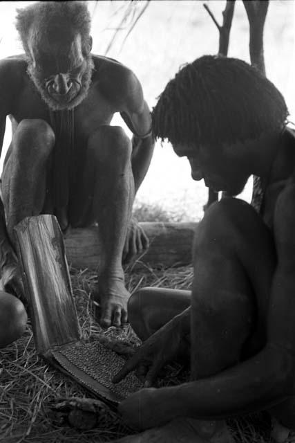 Weaklekek looks at a necklace of Walimoken under an oléa