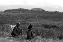 A young boy and an old man sit near the pond on the Tokolik, waiting to join the Warabara