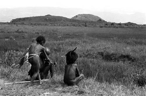 Young boys and an old man sit near the pond on the Tokolik, waiting to join the Warabara