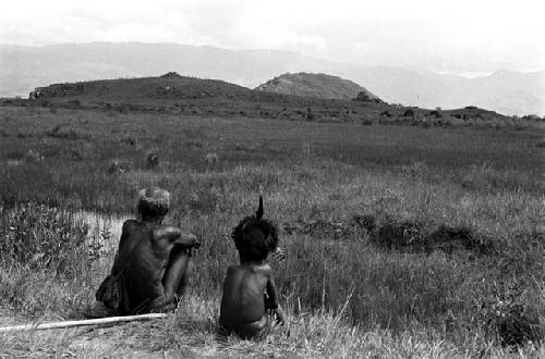 A young boy and an old man watch the distant war