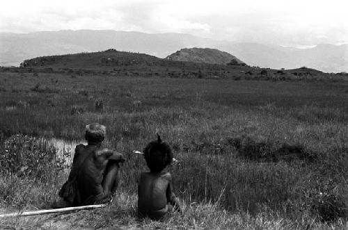 A young boy and an old man watch the distant war